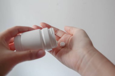 Kadın ellerini kapat ve şişeden eline ilaç tabletleri dök.