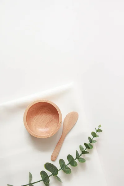 Wooden small bowl and white fabric background for cosmetic products. top view, copy space.