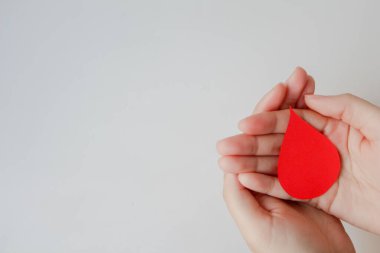 Beyaz arka planda kağıttan yapılmış el yapımı kan damlası şekli, fotokopi alanı, üst görünüm. Kan bağışı konsepti, dünya kan bağışı günü.