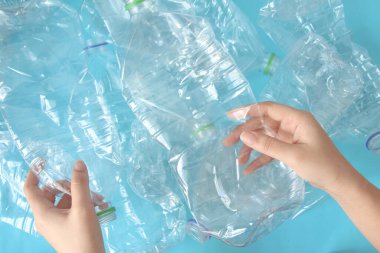 Mavi arka planda plastik şişeleri tutan el manzarası. Geri Dönüşüm ve Dünya Çevre Günü kavramı