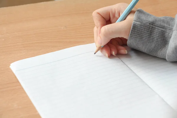 close up woman hand with pencil writing on notebook. journal, plan, goals.