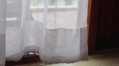 Penceredeki şeffaf perde, rüzgarın hafifçe hareket ettirdiği....