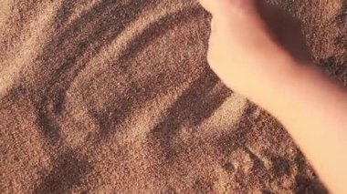Woman drawing heart shapes in sand on river beach. Love and togetherness concept. Real time