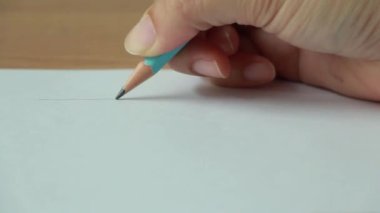 Hand drawing a flat line with a black pencil on paper. close up.