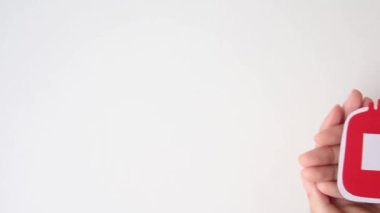 hand holding bloody bag shape made from paper on white background, copy space, top view. blood donation concept, world blood donor day