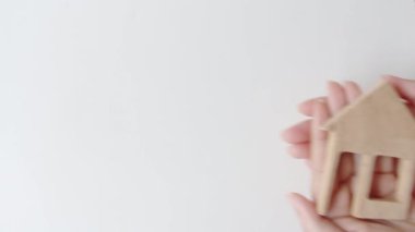 Wood house model in woman hands. Mortgage offers,home care and family house insurance concept.
