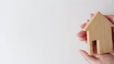 Wood house model in woman hands. Mortgage offers,home care and family house insurance concept.