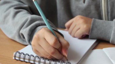 Kadın elleri masa başında boş bir deftere yazı yazıyor..