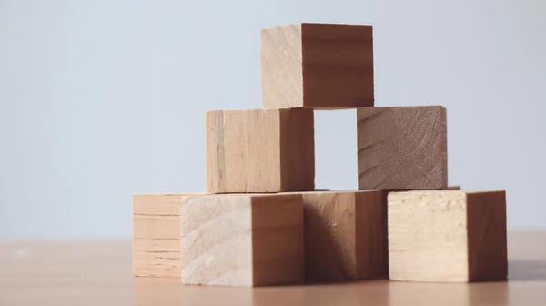 Wood cube on top of wood block tower Business risks.