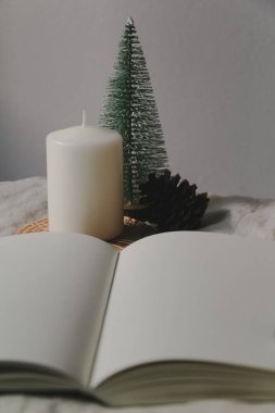 Dekoratif mumlar, minyatür bir Noel ağacı ve masada çam kozalakları..