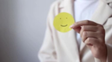 Woman hands holding yellow smile face paper, good feedback rating,think positive, customer review, assessment, world mental health day, Compliment Day.