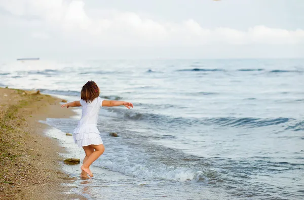 幸せな女の子のダンスは日没の白いドレスでビーチで実行再生自由と幸福の概念 — ストック写真