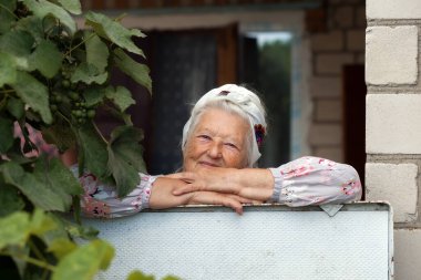 Bahçesinde elinde çiçeklerle dolaşan çok yaşlı bir kadının portresi. Büyükanne ve büyükbaba günü. Yaşlılar için hobiler.