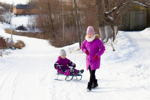 Güzel kış Park çabukluğu ile eğlenmek iki komik küçük kız. Şirin çocuk bir karda oynarken. Çocuklar için kış aktiviteleri.