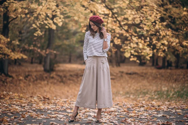公園で秋にブルネットの女性の肖像画。フランス式。ベレー帽とストライプのブラウスの女性 — ストック写真