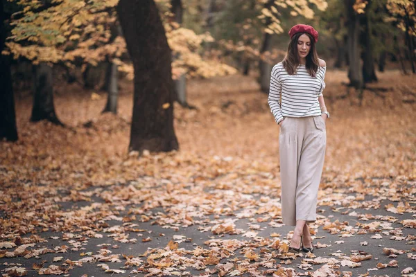 Sonbaharda parkta yürüyen kırmızı bereli güzel esmer bir kadın.