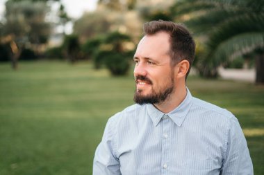 Kamera açık görünen mutlu olgun adam portresi. Üst düzey işadamı sakallı günbatımında güveniyor. Şehir içinde geçmiş ile gülümseyen iş adamı closeup yüzü.