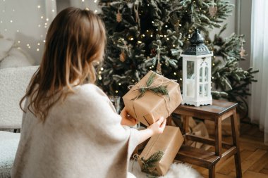 Kış tatili ile kutlanan paketlenmiş Noel hediyelerine odaklan, hazırlık hediyelerini hatırlat, dekore edilmiş ağacın yanında poz ver.