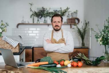 Yeşil malzemeleri ve baharatlı otları olan yakışıklı bir adam mutfakta sağlıklı yemek hazırlıyor.