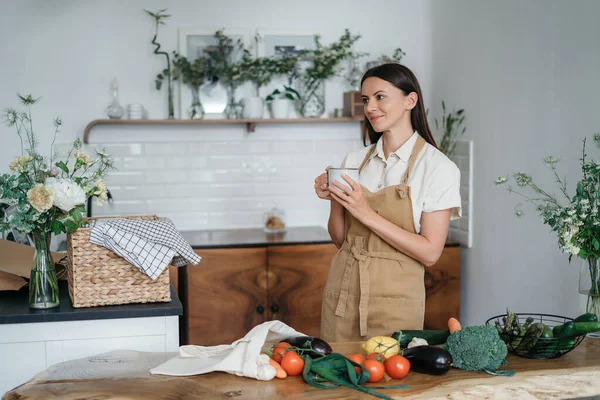 Mutfakta sağlıklı yemek yapmayı düşünen yeşil malzemeli güzel bir kadın. Sağlıklı ve sağlıklı olma kavramı