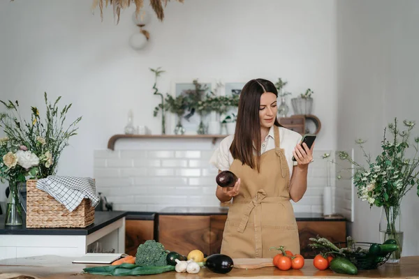 Csinos nő zöld összetevőkkel gondolkodik, egészséges ételeket főz a konyhában. Egészséges és wellness koncepció — Stock Fotó