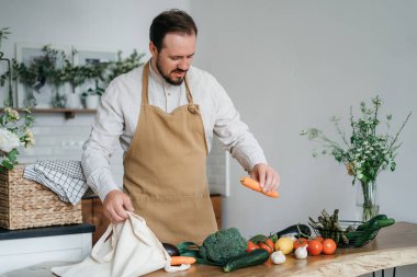 Mutlu genç adam romantik bir akşam yemeği hazırlıyor sebze tarifi arıyor diyet yemek kitabı uygulaması akıllı telefon kullanıyor, elinde telefonla telefon tutuyor mutfak içinde sağlıklı vejetaryen yemeği salatası pişiriyor.