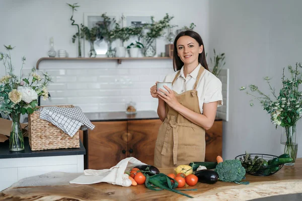 Yeşil malzemeleri ve baharatlı otları olan güzel bir kadın mutfakta sağlıklı yemek pişiriyor. Sağlıklı ve sağlıklı olma kavramı