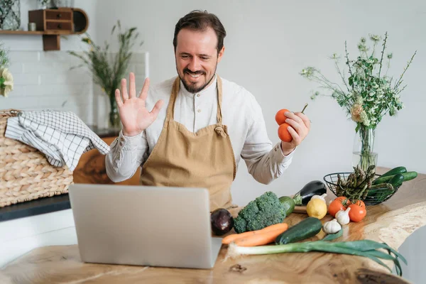 Evdeki mutfakta dizüstü bilgisayarda yemek tarifi arayan bir adam.
