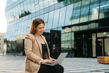 Resmi olarak genç bir bayanın telefonuyla mesajlaşırken, dizüstü bilgisayar kullanırken, bankta otururken, sosyal medyada serbest çalışan genç bir bayanın sohbet ederken yan görüntüsü.