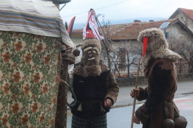 Bulgaristan 'ın Godech kenti - 1 Ocak 2022: Geleneksel kostümlü mumyalar 2022 yılının ilk gününde Godech sokaklarını gezdiler. Kukeri isimli maskeli insanlar dans ediyor ve kötü ruhları korkutmak için gösteri yapıyorlar.