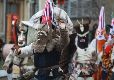 Bulgaristan 'ın Godech kenti - 1 Ocak 2022: Geleneksel kostümlü mumyalar 2022 yılının ilk gününde Godech sokaklarını gezdiler. Kukeri isimli maskeli insanlar dans ediyor ve kötü ruhları korkutmak için gösteri yapıyorlar.