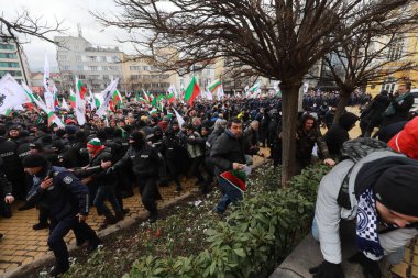 Sofia, Bulgaria - January 12, 2022: Police officers resist people during a protest against green certificate and vaccination against COVID-19 in fort of Bulgarian Parliament in Sofia. 