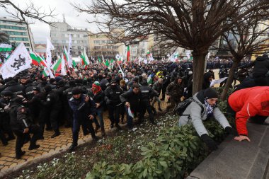 Sofia, Bulgaria - January 12, 2022: Police officers resist people during a protest against green certificate and vaccination against COVID-19 in fort of Bulgarian Parliament in Sofia. 