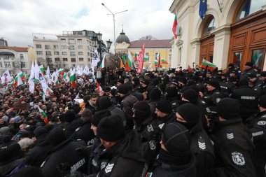 Sofia, Bulgaria - January 12, 2022: Police officers resist people during a protest against green certificate and vaccination against COVID-19 in fort of Bulgarian Parliament in Sofia. 