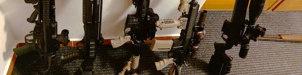 A close-up view of an assault long weapon built against a wall, photo