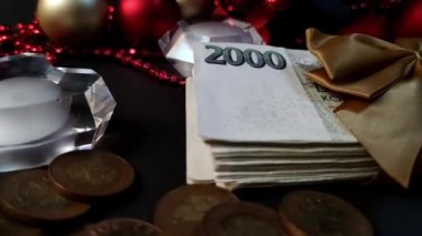 Çek banknotlarının yakın plan görüntüsü altın kurdeleyle bağlanmış, arka planda bir Noel ağacı ve süslemeler, yavaş çekim 