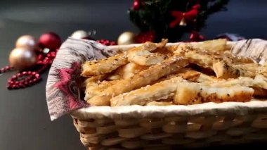 View of puff pastry sticks in a wicker basket, with Christmas decorations in the background, slow motion 