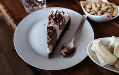 Tabakta çikolatalı pasta, palyaço, arka planda farklı peynir ve fındık türleri, fotoğraf.