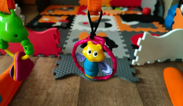 View of a children\'s toy hanging over a children\'s folding play mat, in the background a double-sided foam pad for children, puzzle, photo