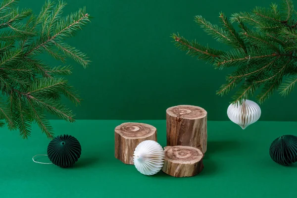 Drei leere Holzpodeste mit rauer strukturierter Oberfläche, weißem Papierweihnachtsschmuck und Tannenzweigen auf grünem Hintergrund. Trendy Naturkosmetik Produktpräsentation Attrappe. Stillleben — Stockfoto