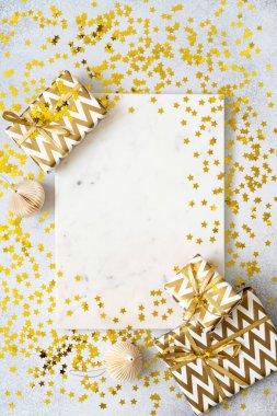 Boş mermer tepsi, Noel hediyeleri, kağıt süsler, gri arkaplanda altın yıldız konfetileri. Doğum günü hediyeleri ve dekorasyonlar. Tebrik kartı modeli. Güzellik kozmetik ürün sunumu. Boşluğu kopyala