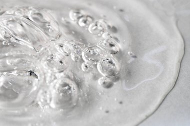 Gri arka plan makrosu köpüklü şeffaf yüz serumu. Hyaluronik asitle kaplanmış sıvı köpüklü jel. Nemlendirici kozmetik ürün dokusu