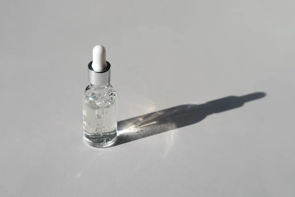 Facial serum with vitamin C in transparent glass bottle with pipette on grey background with trendy hard shadow. Natural cosmetic product for branding. Liquid gel in bottle. Copy space — Stock Photo, Image