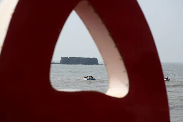 Kolaba kalesinin bir kısmının Alibag sahilinden küçük bir turist teknesinin ilerlediği manzara. Konum: Alibag, Maharashtra, Hindistan Tarih: 08 Kasım 2021