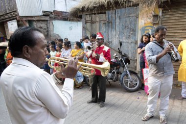Eski Nashik şehrinin sokaklarında bir kutlama alayında rüzgar enstrümanları çalan üç adam. Konumu: Nashik, Maharashtra, Hindistan. Tarih: 01 Mart 2022
