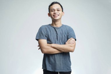 Yakışıklı Asyalı adam izole edilmiş stüdyoda mutlu bir şekilde gülümsüyor.