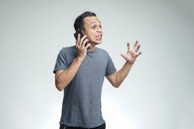 Kızgın Asyalı adam akıllı telefonuyla konuşuyor. Stüdyo arka planında izole