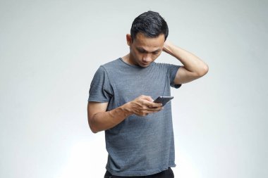 Mutsuz Asyalı adam akıllı telefonuyla sorun yaşıyor.