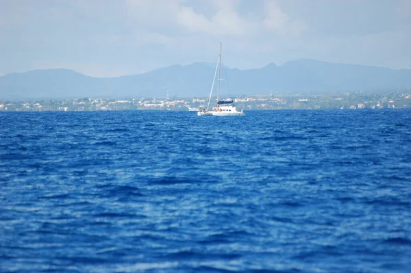 Mauritius açıklarında mavi denizde beyaz yelkenli bir yat.