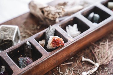 Close up shot of a collection of many different crystals on a messy wiccan witch's altar, with blurred background. Crystal magick